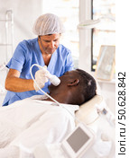 Cosmetologist performing facial cryotherapy procedure on african american. Стоковое фото, фотограф Яков Филимонов / Фотобанк Лори