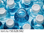 A row of plastic bottles with blue tops. Стоковое AI-изображение, AI-художник Ярославский Максим / Фотобанк Лори