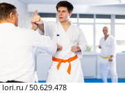 Concentrated guy honing punching techniques during kumite at karate training. Стоковое фото, фотограф Яков Филимонов / Фотобанк Лори