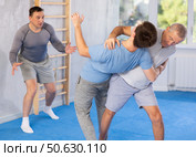 Senior man practicing basic protection skills in training bout during self-defense course. Стоковое фото, фотограф Яков Филимонов / Фотобанк Лори