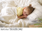 Peaceful adorable baby sleeping on a bed at home. Slumbering little child. Two years old girl sleeps peaceful at domestic room interior background. Serene dream. Cute face close up. Deep kid slumber. Стоковое фото, фотограф Марина Демидюк / Фотобанк Лори