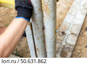 Close-up of a gloved hand securing a metal structure with a bolt, during the construction of a greenhouse or gazebo. Стоковое фото, фотограф Коханова Наталья / Фотобанк Лори