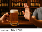 Человек отказывается от кружки пива, показывая жест рукой в баре. Стоковое AI-изображение, AI-художник Башкирова Анна / Фотобанк Лори
