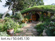 Cozy hobbit hole nestled in a lush garden in hobbiton movie set, new zealand. Стоковое AI-изображение, AI-художник Иван Рябоконь / Фотобанк Лори
