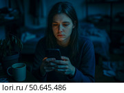 Утомленная апатичная девушка, нервозная и с бессонницей, со смартфоном в руке сидит в соцсетях. В комнате грязно, бардак. Зависимость от соцсетей. Стоковое AI-изображение, AI-художник Sergei Gorin / Фотобанк Лори