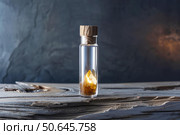 Citrine crystal displayed in glass jar on rustic wood surface. Стоковое AI-изображение, AI-художник Иван Рябоконь / Фотобанк Лори