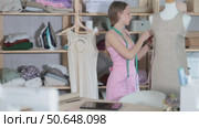 Dressmaker tries on a sample of the dress on a mannequin and checks the quality. Process of making a collection of clothes in a sewing workshop. Стоковое видео, видеограф Яков Филимонов / Фотобанк Лори