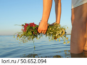 A girl lowers a wreath of wild flowers into water. Стоковое фото, фотограф Владислав Тригуб / Фотобанк Лори