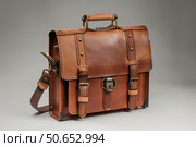 Leather messenger bag standing up with clasps and a grey background. Стоковое AI-изображение, AI-художник Иван Рябоконь / Фотобанк Лори