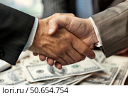 Businessmen shaking hands over stack of money, making a deal. Стоковое AI-изображение, AI-художник Иван Рябоконь / Фотобанк Лори
