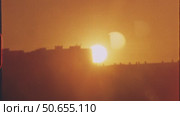 Vibrant orange sunset sinking behind darkened urban skyline, casting warm golden hues across architectural landscape with gradual chromatic transitions, 8 mm film. Стоковое видео, видеограф Данил Руденко / Фотобанк Лори