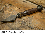 Old roofing tool lying on wooden table top in workshop. Стоковое AI-изображение, AI-художник Иван Рябоконь / Фотобанк Лори