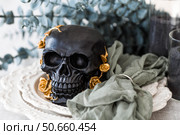 A mysterious black skull with golden roses and pumpkins on serving plates for a Halloween or Day of the Dead party. Стоковое фото, фотограф Photojuli / Фотобанк Лори