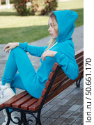 Smiling girl in blue tracksuit sitting on wooden bench outdoors looking at camera. Стоковое фото, фотограф Роготнева Виктория / Фотобанк Лори