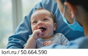 A Joyful Baby Smiles While Being Held by a Caregiver in a Calm Indoor Environment. Стоковое AI-видео, аниматор Sergey Grishin / Фотобанк Лори