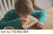 6 years old boy eats instant noodle from box. Child is eating spaghetti. Lunch time. A good appetite. Tasty children food. Close-up portrait. Carbs dinner. Fast food. Kid eating by himself with fork. Стоковое видео, видеограф Марина Демидюк / Фотобанк Лори