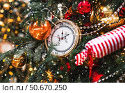 Golden retro clock on a Christmas tree. The clock hands show 12 o'clock. Beautiful background for New Year's Eve or Christmas 2026. Стоковое фото, фотограф Photojuli / Фотобанк Лори