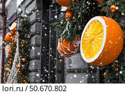Mandarins in a string bag and Christmas tree decorations on the streets of Moscow. Happy New Year 2026. The concept of preparing decorations and ornaments for Christmas. Стоковое фото, фотограф Photojuli / Фотобанк Лори
