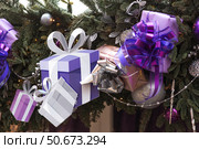 Holiday toys and purple gift boxes on the New Year's tree in Moscow. The concept of buying and giving gifts. New Year's card 2026. Стоковое фото, фотограф Photojuli / Фотобанк Лори