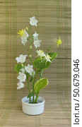 Vertical video of female hand placing bellflower on floral arrangement wit yellow columbine, green hosta leaves and white bells on kenzan holder on straw mat. Floral design as hobby and pleasure. Стоковое видео, видеограф Виктория Катьянова / Фотобанк Лори