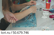 A woman decorates her old jeans with a chain, adding a unique touch to them and giving them a fresh look. Стоковое видео, видеограф Strunov David / Фотобанк Лори