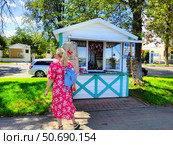 Сувенирный киоск в Ярославле и женщина в ярком платье (2024 год). Редакционное фото, фотограф Ирина Терентьева / Фотобанк Лори