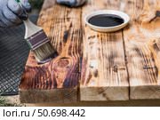 The procedure for protecting and coating wooden boards. A worker applies a protective wood stain with a brush. The process of restoring a hardwood flooring. Стоковое фото, фотограф Photojuli / Фотобанк Лори