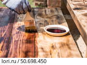 The procedure for protecting and coating wooden boards. A worker applies a protective wood stain with a brush. The process of restoring a hardwood flooring. Стоковое фото, фотограф Photojuli / Фотобанк Лори