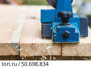 A hand-held electric planer in the hands of a craftsman. A man planing boards with an electric tool. Production of wooden products. Construction, wood processing. Стоковое фото, фотограф Photojuli / Фотобанк Лори