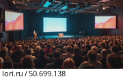 Engaging Speaker Captivating a Large Audience in a Conference Hall With Two Screens; Event Planners and Speakers in Focus. Стоковое AI-видео, аниматор Sergey Grishin / Фотобанк Лори