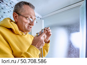 Plumber places sealing ring inside metal nut on flexible hose, ensuring leak-free joint before attaching shower hose in enclosed shower area. Стоковое фото, фотограф Владимир Григорьев / Фотобанк Лори