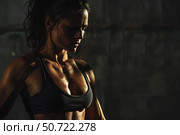 Sweaty female bodybuilder resting after intense workout in dark gym. Стоковое AI-изображение, AI-художник Иван Рябоконь / Фотобанк Лори