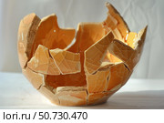 Broken orange ceramic bowl representing fragility and imperfection. Стоковое AI-изображение, AI-художник Иван Рябоконь / Фотобанк Лори