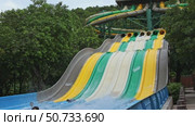 Happy people sliding down a water slide in aqua park, enjoying fun and summer activity. Excitement, playfulness, refreshing outdoor entertainment. Slow motion footage. Редакционное видео, видеограф Ирина Михайличенко / Фотобанк Лори