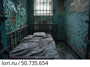 Derelict prison cell with peeling paint and barred window. Стоковое AI-изображение, AI-художник Иван Рябоконь / Фотобанк Лори