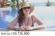 Beautiful young girl in swimsuit and straw hat relaxing by the swimming pool during summer holiday. Copy space. Summer and vacation, sunbathing wellness Lifestyle concept. High quality footage. Стоковое видео, видеограф Ирина Михайличенко / Фотобанк Лори