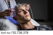 Doctor examining patient brain using electroencephalography headset. Стоковое AI-изображение, AI-художник Юрий Поздников / Фотобанк Лори