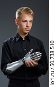 Young man holding bionic prosthetic arm, embracing future technology. Стоковое AI-изображение, AI-художник Юрий Поздников / Фотобанк Лори