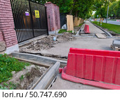 Ремонт тротуара возле кирпичного забора в Москве. Редакционное фото, фотограф Мария Сергеева / Фотобанк Лори