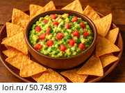 A Bowl of Fresh Guacamole Surrounded by Crispy Tortilla Chips Perfect for Snacking or Sharing at Gatherings and Celebrations. Стоковое AI-изображение, AI-художник Башкирова Анна / Фотобанк Лори