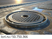 Decorative manhole cover on a paved city street. Municipal water supply and sewerage. Стоковое AI-изображение, AI-художник Коханова Наталья / Фотобанк Лори