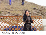 ELANTSY, IRKUTSK REGION, RUSSIA - July 5, 2025: Erdynskie Games – festival of nomadic peoples of Eurasia. Beautiful Buryat girl on an open stage takes part in beauty contest and sings national song. Редакционное фото, фотограф Виктория Катьянова / Фотобанк Лори