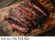 Sliced brisket resting on cutting board with sauce drippings. Стоковое AI-изображение, AI-художник Иван Рябоконь / Фотобанк Лори