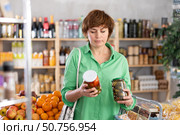 Woman make choice choose consider canned vegetables in store. Стоковое фото, фотограф Яков Филимонов / Фотобанк Лори