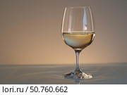 Glass of white wine reflecting on a surface with brown background. Стоковое AI-изображение, AI-художник Иван Рябоконь / Фотобанк Лори