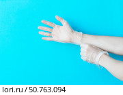Human hands puting on vinyl disposable gloves above bright blue background with copy space. Safety first concept. Стоковое фото, фотограф Акимова Надежда / Фотобанк Лори