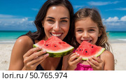 Mom and little daughter are eating watermelon on the tropical shore. Стоковое AI-изображение, AI-художник Ирина Гильмуллина / Фотобанк Лори
