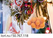 Happy New Year 2026. Mandarins in a string bag and Christmas tree decorations on the streets of Moscow. The concept of preparing decorations and ornaments for Christmas. Стоковое фото, фотограф Photojuli / Фотобанк Лори