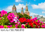 Спасская башня Московского Кремля и яркие красные цветы в летний солнечный день. Москва. Россия. Редакционное фото, фотограф E. O. / Фотобанк Лори