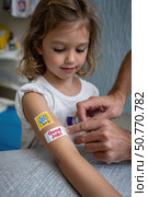 Doctor applying adhesive bandage with good job message to girl's arm after injection. Стоковое AI-изображение, AI-художник Юрий Поздников / Фотобанк Лори
